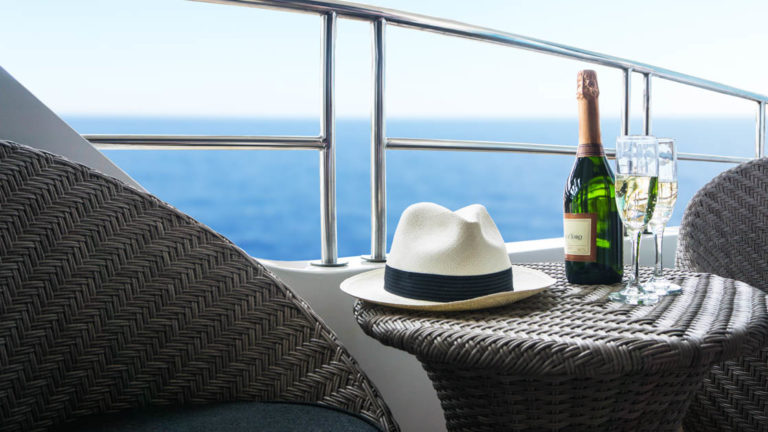 Galapagos Infinity outdoor table and chairs with wine and panama jack hat on the table overlooking the ocean in the Galapagos.
