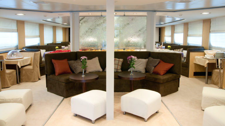 Harmony V yacht lounge are with couches, ottomans, chairs and small tables.