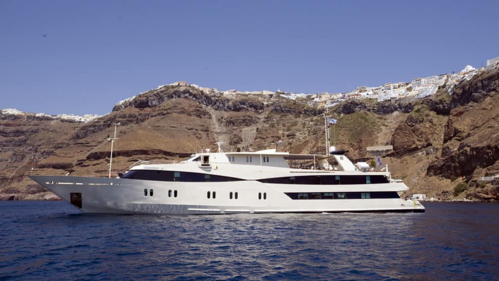 Harmony V motor yacht exterior anchored off the coast of Santorini.