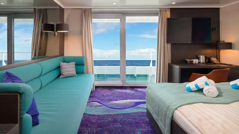 Grand Suite aboard Hondius and Janssonius polar small ships, with teal and purple accents, couch, double bed & balcony.