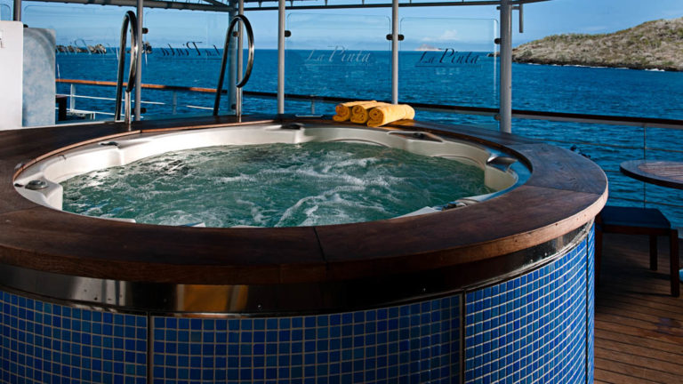a hot tub on the deck of the la pinta galapagos yacht on a sunny day