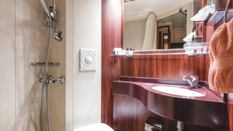 Lord of the Glens stateroom bathroom with shower, vanity, toilet and storage.