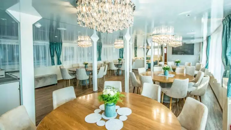 Markan Dining Room with round tables, chairs, large windows and chandeliers.