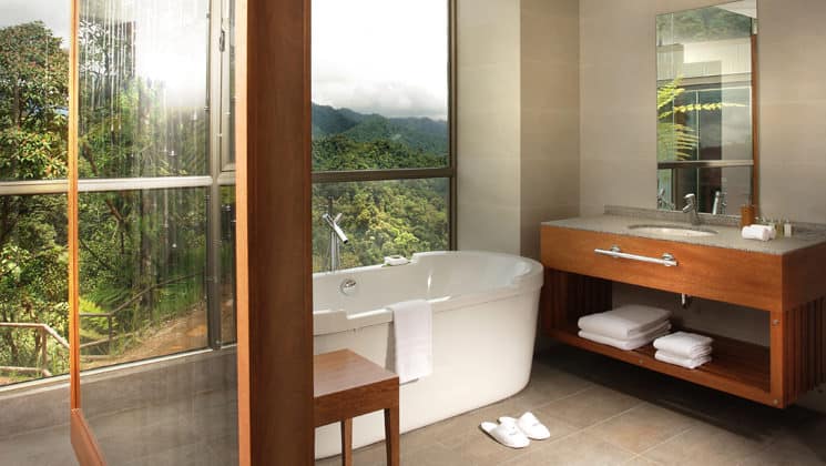 The Yaku Suite bathroom with a full tub, vanity, and large windows overlooking the jungle at the Mashpi eco lodge, a luxury wellness retreat in Ecuador