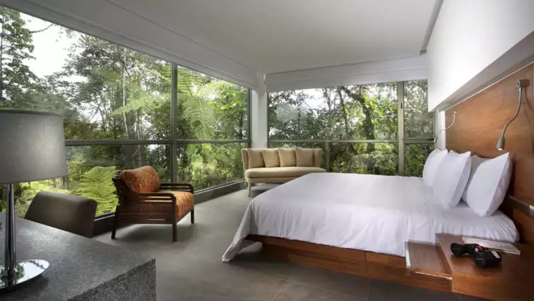 The Yaku King Suite has a large bed, fresh linens, and panoramic view of the jungle at the Mashpi eco lodge, a luxury wellness retreat in Ecuador
