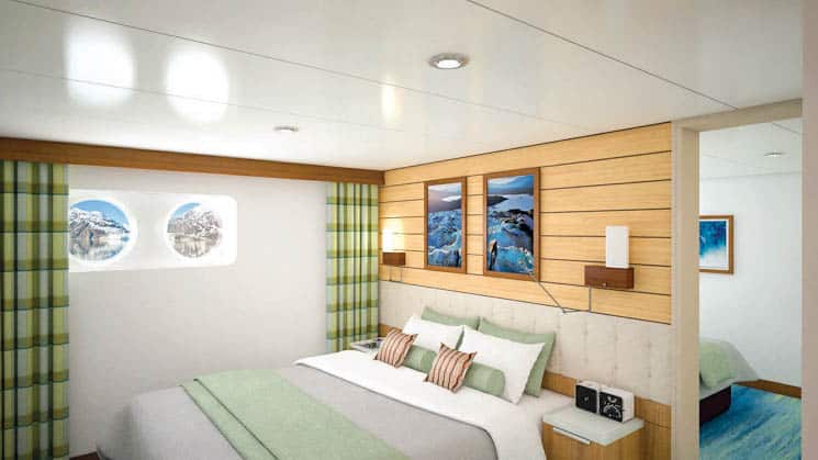 Large bed and two portholes in Category 2 cabin aboard National Geographic Quest luxury expedition ship