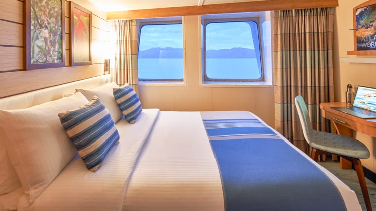 Queen bed, desk, chair and two large windows in cabin aboard National Geographic Venture expedition ship