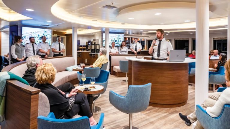 Lounge with captain giving a talk to guests while they sit back aboard National Geographic Venture Ship