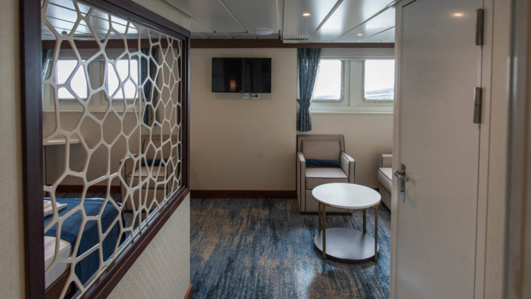 entrance of the owner suite aboard Ocean Adventurer with a mirror, stool and chairs