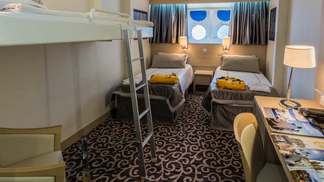 Triple cabin aboard Ocean Diamond polar expedition ship, with 3 twin beds, desk, couch & 2 portholes.