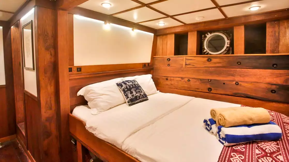 room with large bed and wooden walls aboard the ombak putih small ship