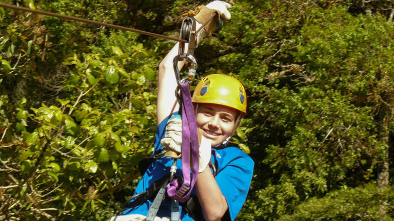 a teen with a yellow helmet ziplining in the jungle canopy on the panama family adventure land tour