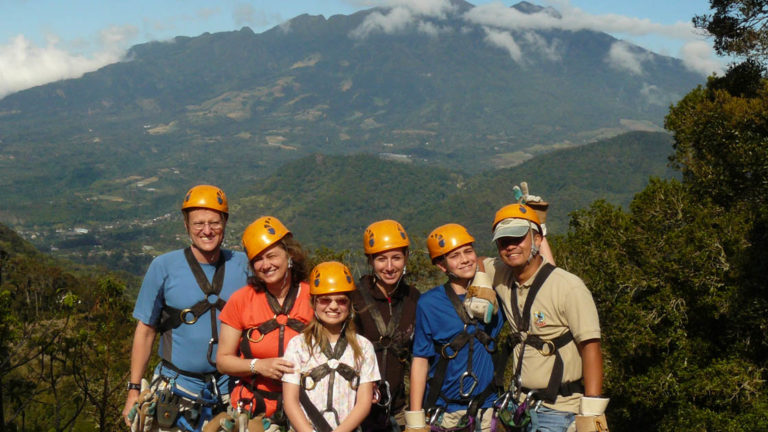 group of adventure travelers with harnesses and orange helmets with mountains in the background on the panama family adventure land tour