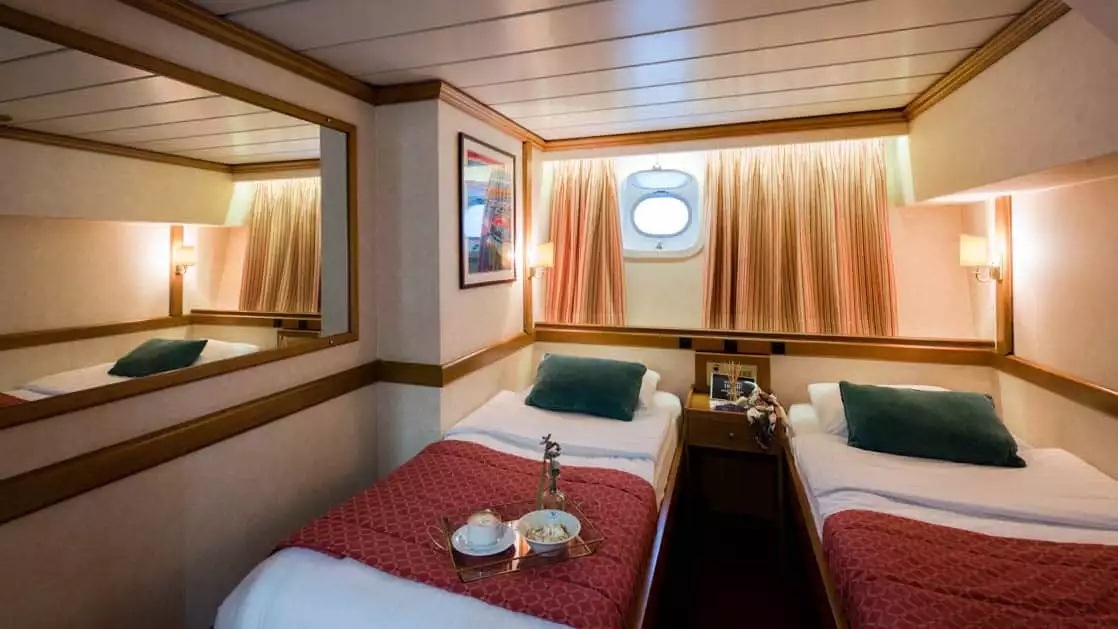 panorama Mediterranean luxury yacht room with 2 beds and a porthole above them