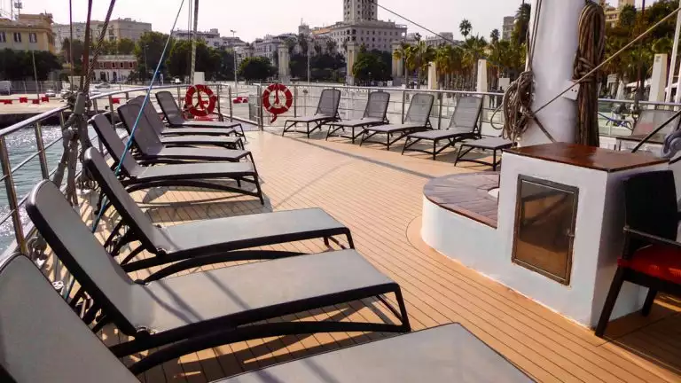 Upper sun deck with lounge chairs looking out at a city in the background aboard Panorama II