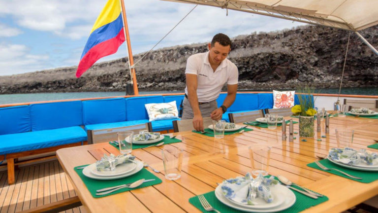 crew member setting the al fresco dining table on the deck aboard Passion