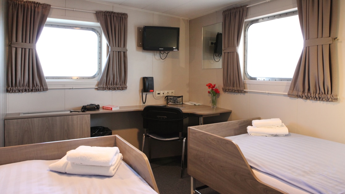 Twin Deluxe cabin with 2 windows and a table aboard Plancius polar vessel