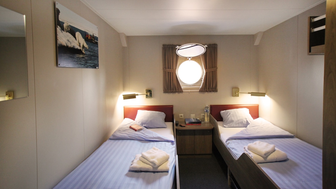 cabin with 2 beds and a porthole aboard Plancius polar ship