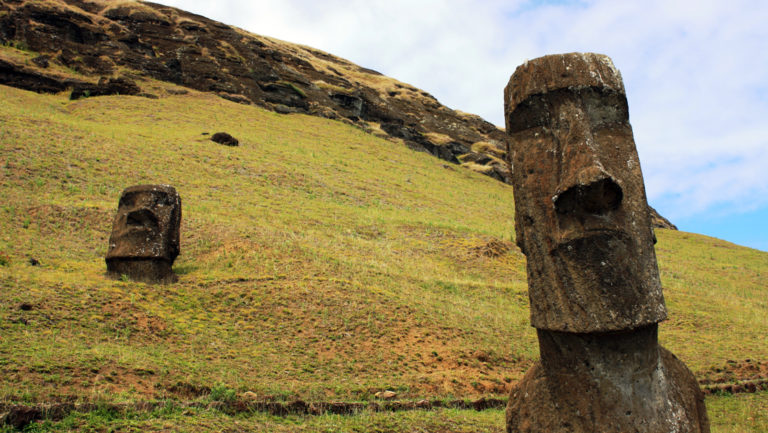 Two Rapa Nui Moai statues on a green hill.