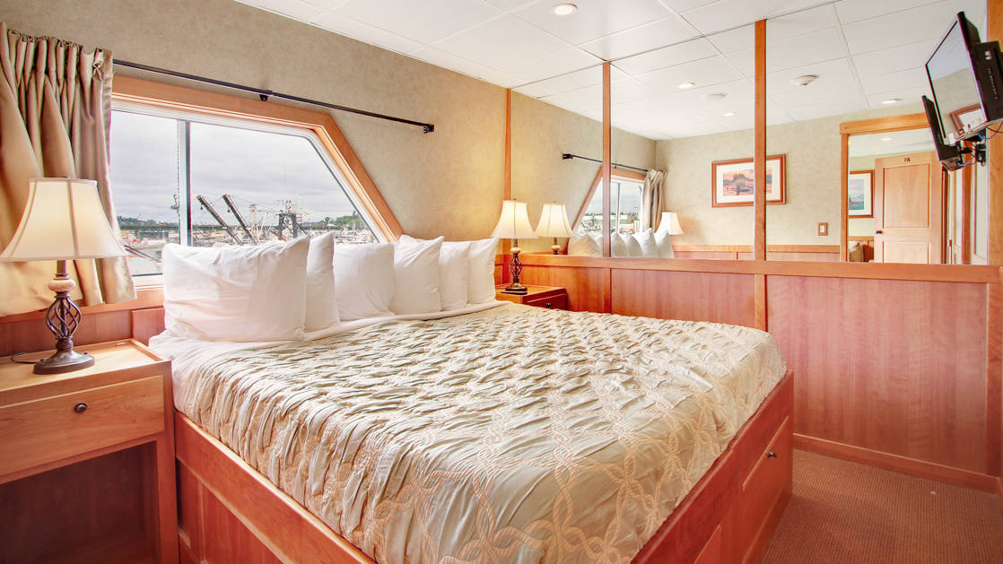 king bed with cream and white pillows on top of it and opening to adjoining room aboard the Safari Explorer Hawaii small ship
