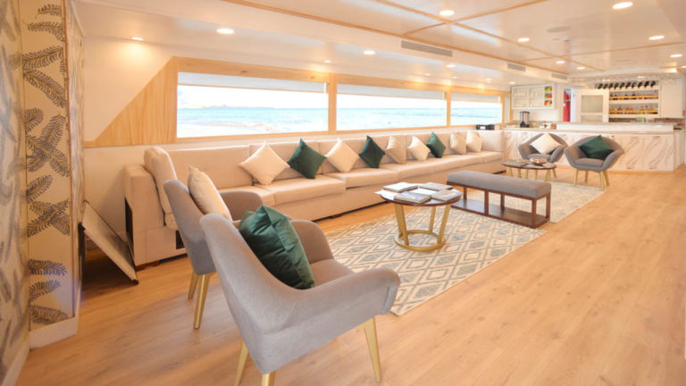 Lounge area with chairs and pillows lining large window viewing the ocean aboard Galapagos small ship Sea Star Journey