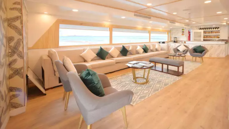 Lounge area with chairs and pillows lining large window viewing the ocean aboard Galapagos small ship Sea Star Journey