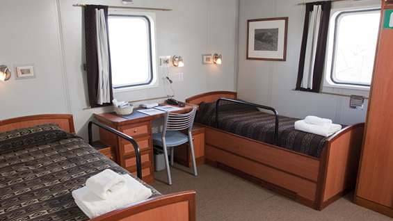 Superior Twin cabin aboard Ushuaia with desk and two twin beds.