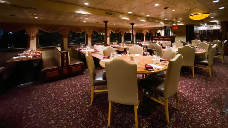 Dining room with tables in center and booths along windows aboard Wilderness Legacy expedition ship