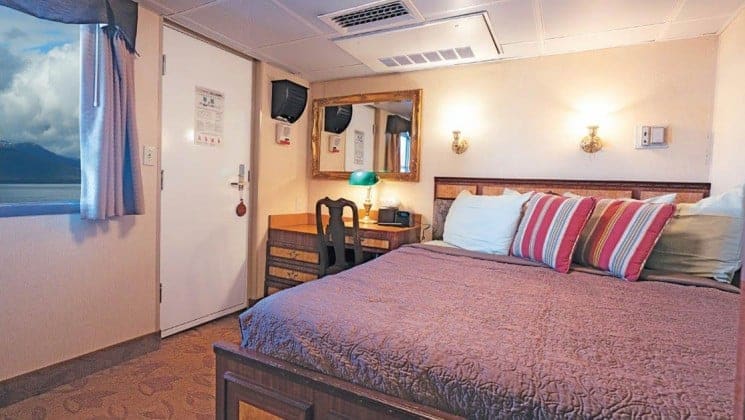 Pathfinder stateroom with large bed, desk, chair aboard Wilderness Legacy expedition ship