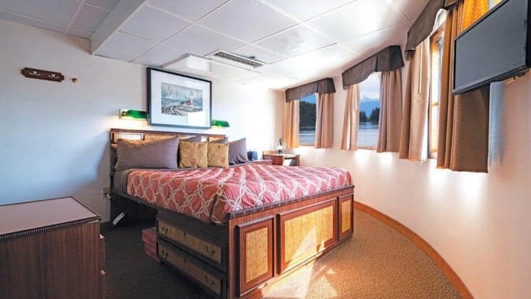 Large bed, wraparound windows in S.S. Legacy expedition ship Jr. Commodore Suite