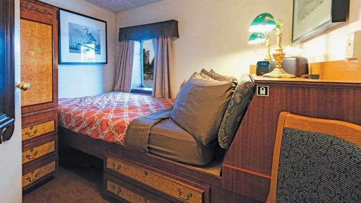 Bed, dresser, window in Navigator Stateroom aboard Wilderness Legacy expedition ship
