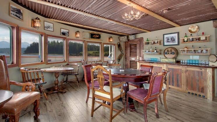 Tables, chairs, window-lined walls in bar area aboard Wilderness Legacy expedition ship