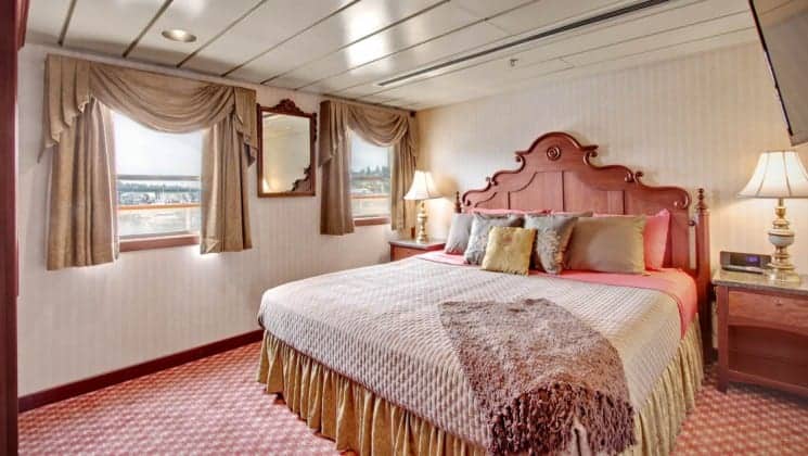 Large bed, two nightstands, two large windows is Commodore Suite aboard Wilderness Legacy expedition ship
