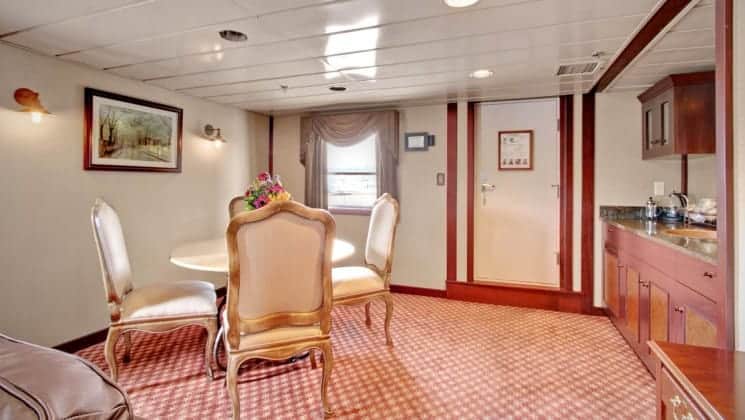Dining table with four chairs near bar in suite aboard Wilderness Legacy expedition ship