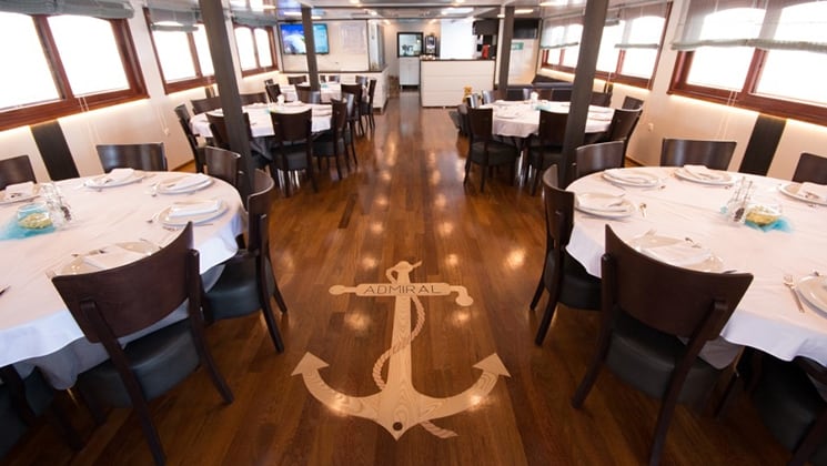 Tables set in the dining room with anchor design in the wood flooring aboard Admiral.