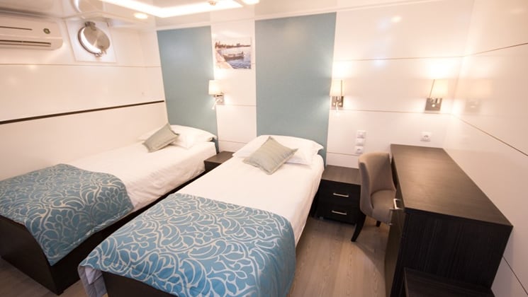 Cabin aboard Admiral with two twin beds and portholes.