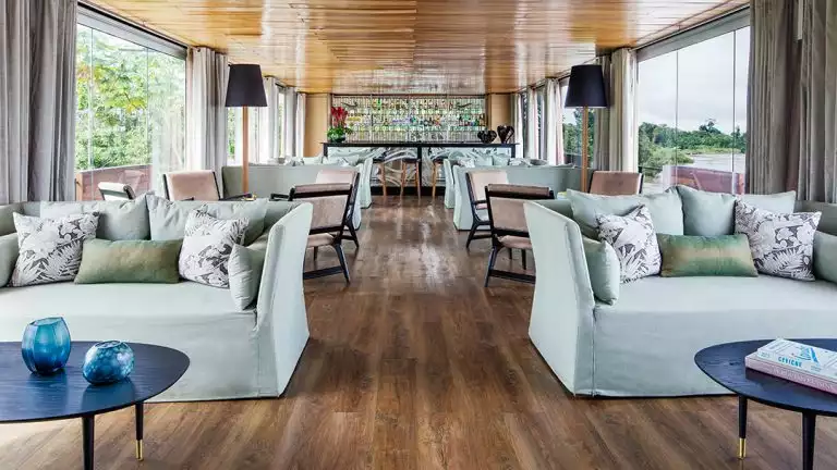 Bar and lounge of a small size cruise ship with couches and bar in the back.