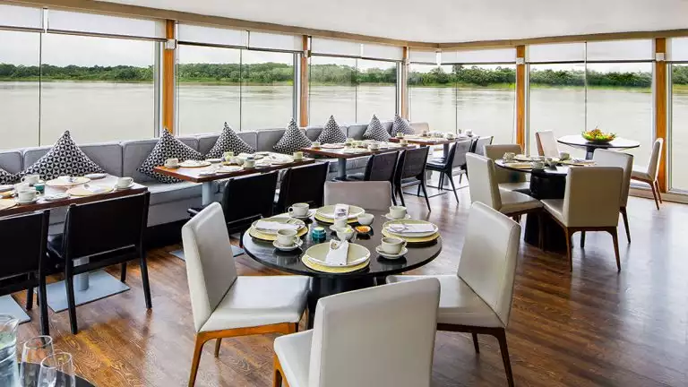 aria dining room with white chairs and large windows to view the amazon river