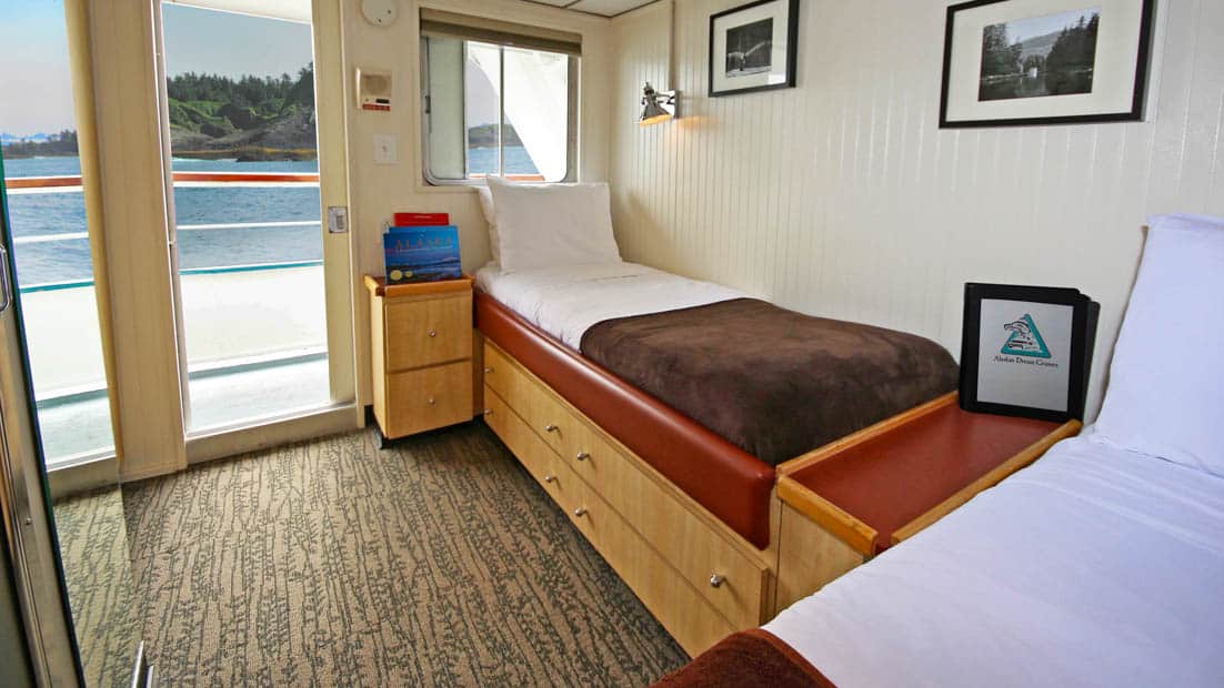Category AA stateroom aboard Baranof Dream with two single beds, window, and doorway.