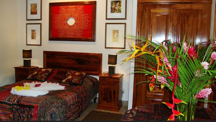 room in the candelaria lodge in guatemala with a large bed, flowering plant and pictures on the wall