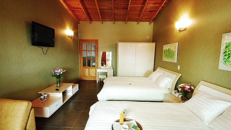 room at casa grande bambito with two beds, green walls and a door leading to another area