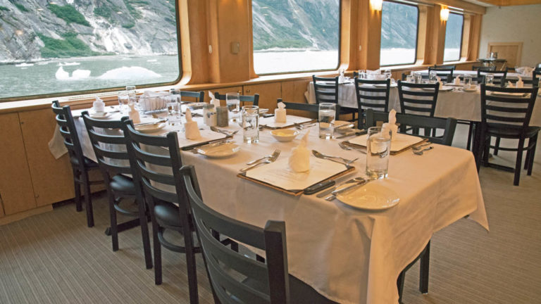 Dining room with several tables by the windows aboard Chichagof Dream