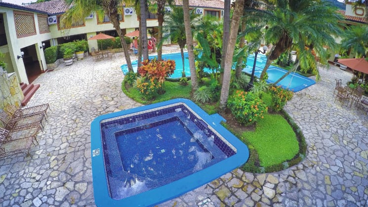 pool area of the clarion copan hotel in guatemala with a separate hot tub and green foliage throughout it
