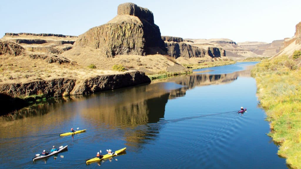 Columbia & Snake Rivers Journey small ship cruise passengers kayaking on calm waters in a sunny pacific northwest gorge