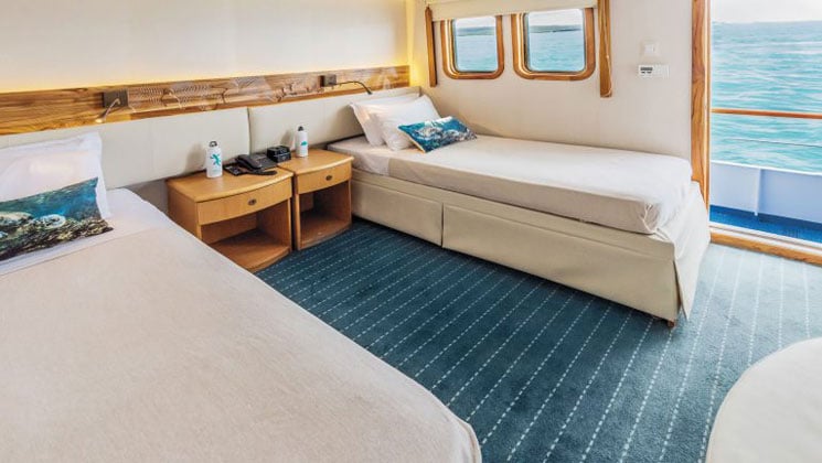 Interior of Junior Cabin with 2 twin beds and two large windows aboard Coral I & Coral II yachts in the Galapagos Islands