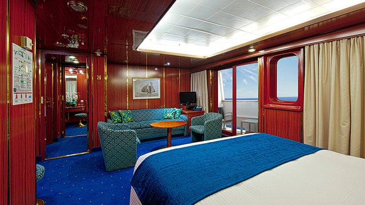 Suite 604 on the Corinthian small ship with a bed and large windows and a couch.