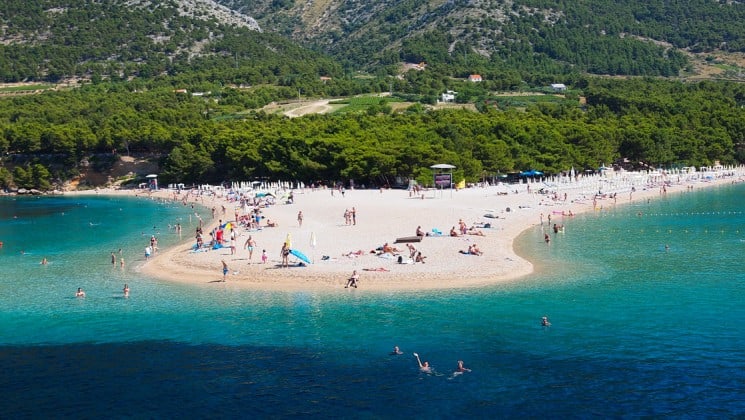looking down at a beautiful croatia beach filled with adventure travelers in the middle of the day
