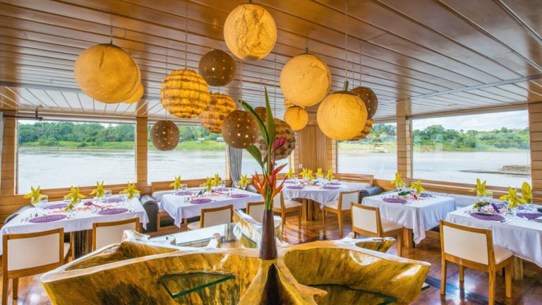 Dining room of the Delfin II amazon small ship, outfitted with luxurious chairs and tables sourced from the region.