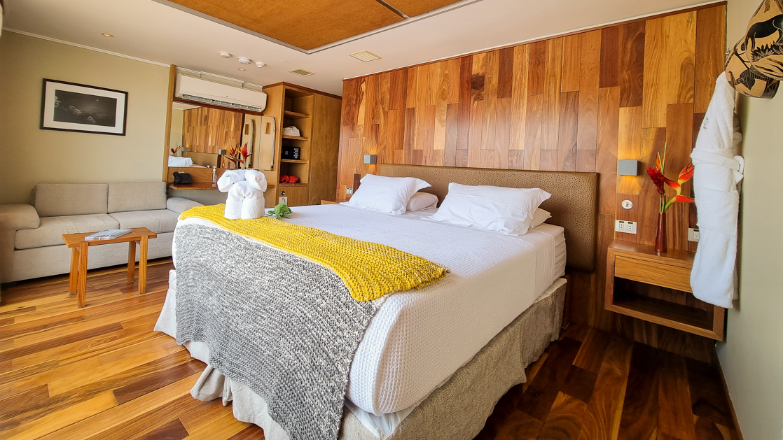 Beautiful wood finishea with a large bed and couch featuring a bird of paradise on one of the two night stands aboard the Delfin III