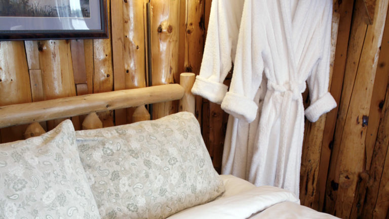 Two robes hang next to a double bed inside a cabin at Winterlake Lodge, an Alaska resort recognized by National Geographic for its wilderness experience